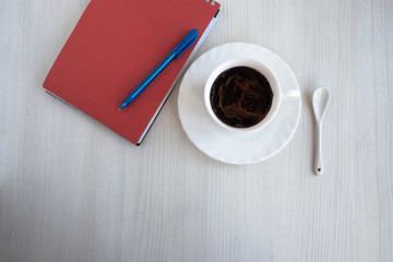 notebook, pen and cup of coffee on white table