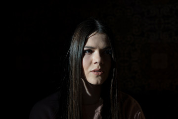 A shadow hides half the face of a girl when she sits in a cafe in the evening