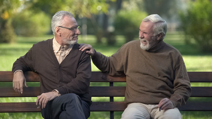 Obraz premium Elderly male friends smoking cigar, friends enjoying rest in park together