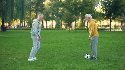 Senior sportsmen playing football on weekend in park, active leisure, friendship