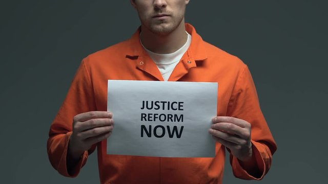 Justice reform now demanding on card in hands of Caucasian prisoner, fairness