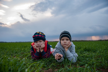 happy children playing in field sown with winter wheat against backdrop of rain clouds. Brothers...