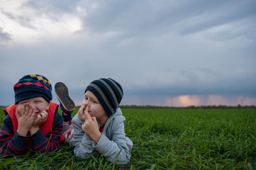 happy children playing in field sown with winter wheat against backdrop of rain clouds. Brothers...
