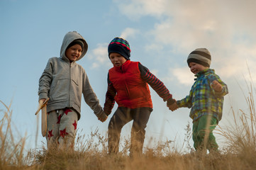 Three happy children playing in field sown with winter wheat against backdrop of rain clouds....