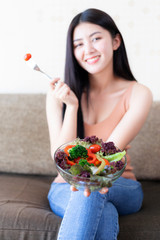 Beautiful beauty woman Asian cute girl feel happy eating diet food fresh salad for good health in the morning , enjoying time in her home white bedroom background - lifestyle beauty woman concept