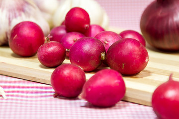 red radish, fresh garlic, red onion, garlic cloves on a blue background.