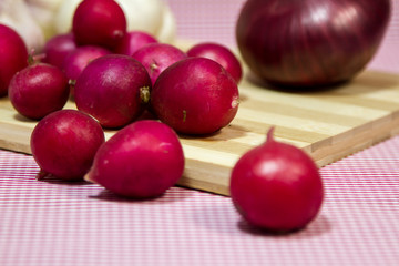 Healthy vegetables on a pink background. Fresh garlic (allium, Bulbus Allii Sativ) is a real storehouse of nutrients and trace elements. Red sweet onions (solaninum) - natural antioxidant. Red radish 