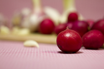 Healthy vegetables on a pink background. Fresh garlic (allium, Bulbus Allii Sativ) is a real storehouse of nutrients and trace elements. Red sweet onions (solaninum) - natural antioxidant. Red radish 
