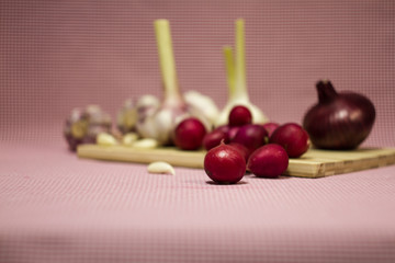 Healthy vegetables on a pink background. Fresh garlic (allium, Bulbus Allii Sativ) is a real storehouse of nutrients and trace elements. Red sweet onions (solaninum) - natural antioxidant. Red radish 