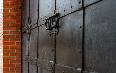 old black castle door with bolt in red brick wall