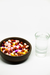 Glass of water inside a glass with colorful medicines