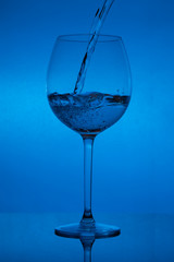 Filling the glass, pouring wineglass on blue background