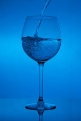 Filling the glass, pouring wineglass on blue background
