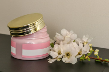 Jar of cosmetic cream and flower