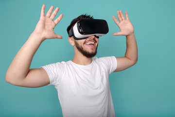 Nice bearded man trying VR headset and exploring another world on the colorful background.
