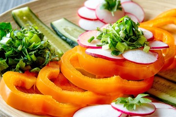 Spring vegetable salad with pepper, radish, onion, parsley and cucumbers.