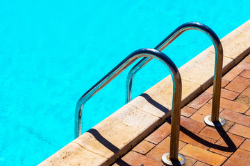 Grab bars ladder in the blue swimming pool