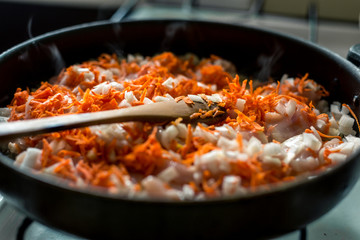 Cooking for soup, chopped carrots and onions are fried in a pan