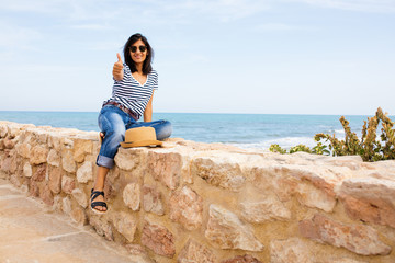Young indian woman doing okay in front of the sea
