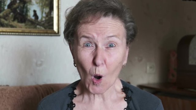 Surprised positive elderly woman, close-up. Grandmother gawking and opening her mouth with delight