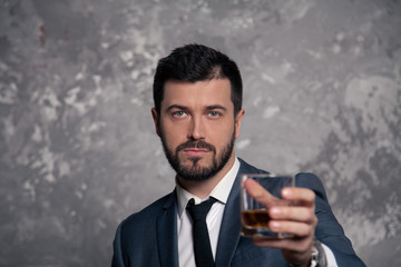 portrait of a good looking handsome businessman with a glass of whisky. wearing suit and a tie