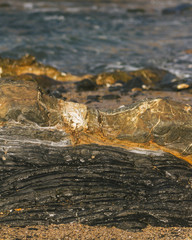Close-up of black and golden rock on the beach