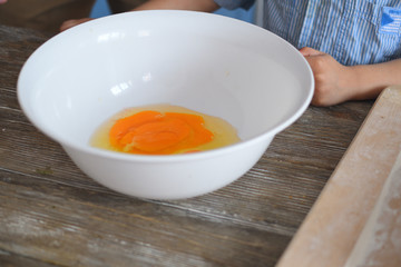 White Bowl with broken eggs on a wooden table