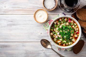 Traditional Russian summer cold soup okroshka with kvass in bowl on wooden background. Top view. Copy space.