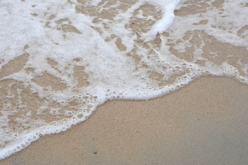 Beautiful soft waves of Blue Ocean with Sandy Beach Background close up. Sea sand wallpaper