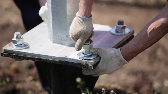 Installation of power lines. Workers tighten the nuts on the bolts with spanners. The hands of the workers. Engineering structures. Close-up.