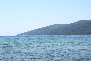 Fototapeta na wymiar Beautiful minimalistic seascape of calm sea, sandy beach, blue sky, Greece. Horizontal.