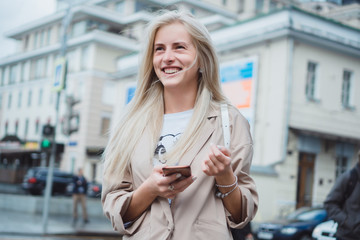 Young beauty woman using smartphone in hand, in the street, outdoor hipster portrait