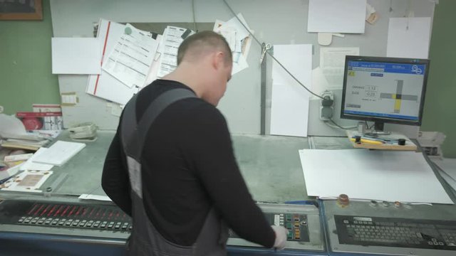 A man works in a printing house and checks the print settings