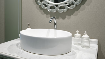 Luxury faucet mixer on a round bowl white sink in a beautiful beige gray bathroom