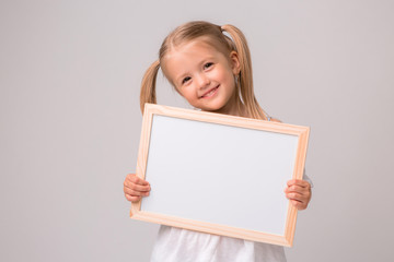 girl holding a white Board .Cute little girl with a white sheet of paper.white background.copy...