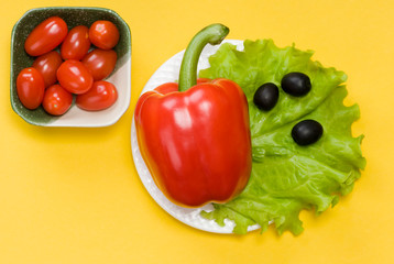 still life of bell pepper, tomato cherry, lettuce and olives on yellow background