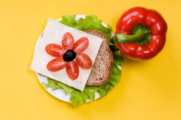 sandwich with vegetables on a white plate on a yellow background