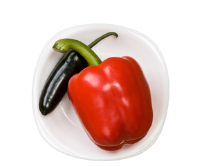 Single green jalapeno pepper and red bell pepper on plate isolated on white background