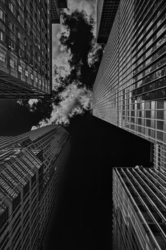 Fototapeta Low view on skyscrapers in Manhattan in black and white with clouds.