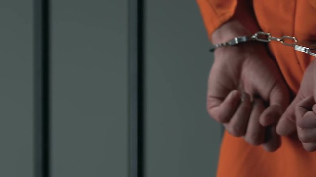 Prisoner in handcuffs walking in cell, waiting for court decision, justice