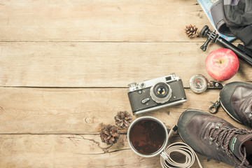 Boots, backpack, compass and other camping gear on a wooden background. The concept of hiking in the mountains or the forest, tourism, tent rest, camp. Flat lay, top view.