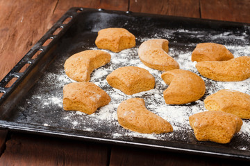 Handmade cookies on baking sheet on wooden background.