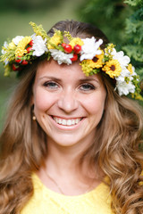 Portrait young girl in yellow dress with Flower wreath for head. Walking in park, Warm summer day.