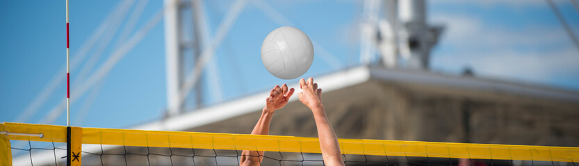Hands playing beach volleyball