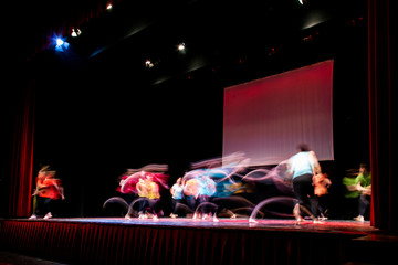 Group of dancer in colored clothes dancing on the stage in long exposure