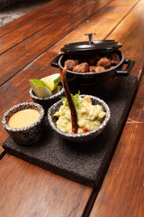 Carnitas en Lolita con guarnición de guacamole y chile acompañado de limones y salsa picante