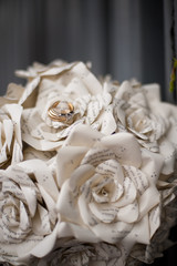 wedding rings on a bouquet of paper flowers