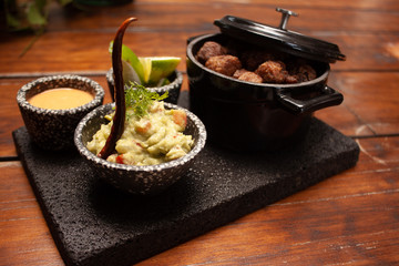 Carnitas en Lolita con guarnición de guacamole y chile acompañado de limones y salsa picante