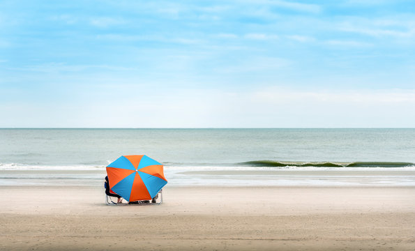 Orange and blue beach umbrella on beautiful beach with blue sky