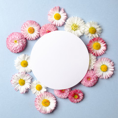 Obraz premium Spring holiday concept. Creative layout made of colorful flowers and blank circle-shaped paper card on pastel blue background. Flat lay composition. Top view, overhead